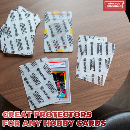 Product photo showing Ding Defend 4 x 6 trading card shipping protectors laid out on a table with hobby cards inside semi-transparent plastic sleeves